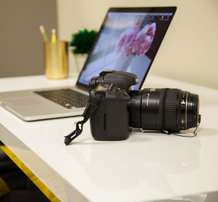 professional camera and laptop sitting on a desk