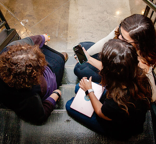 Marketing professionals sitting on stairs viewing social media on mobile