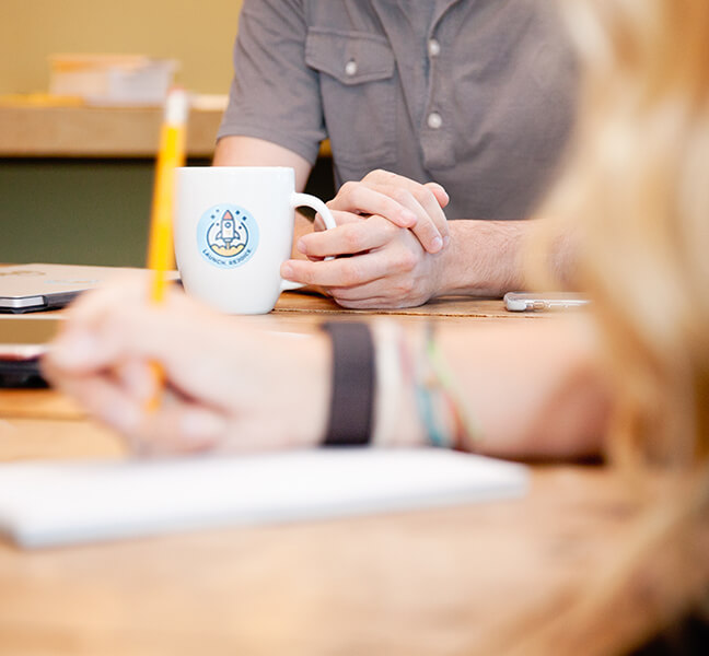 Close-up of hands holding coffee cup in a team meeting