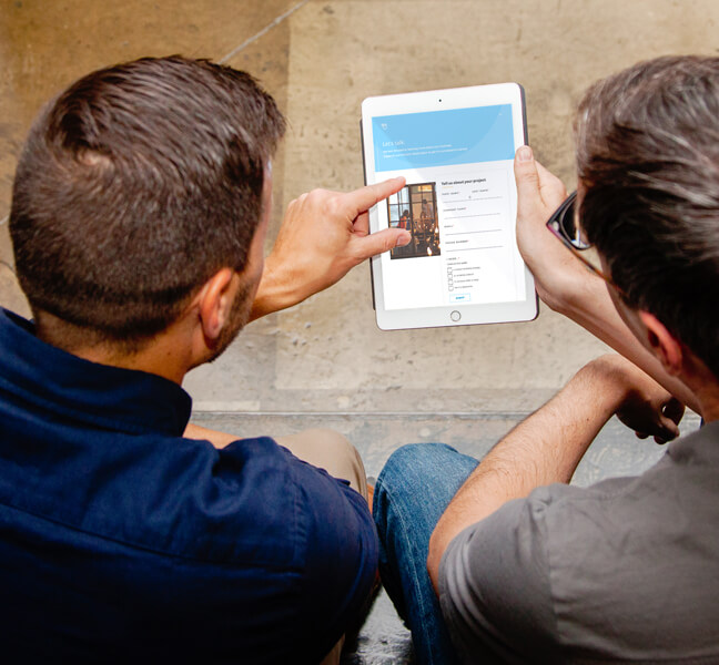 Two people viewing a website form on a tablet