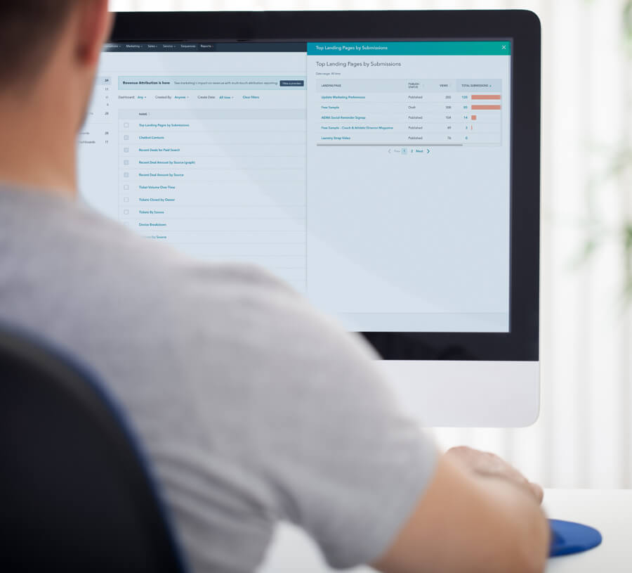 Man reviews sales-related findings in Hubspot marketing reporting dashboard