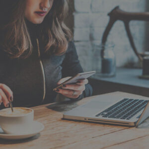 woman at laptop with phone in coffee shop