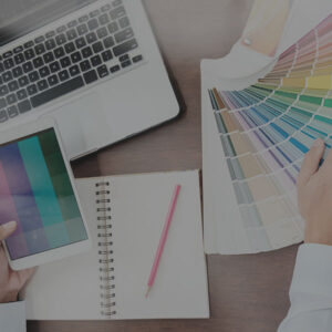 web designer with color options spread out on a desk next to a laptop