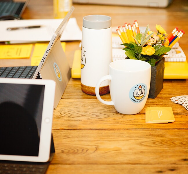 TBH Creative mug and tumbler sitting on meeting table with tablets and pencils