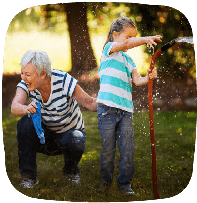 grandmother playing with hose with granddaughter