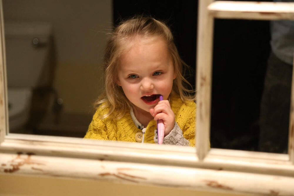 Girl brushing her teeth in mirror at dentists office