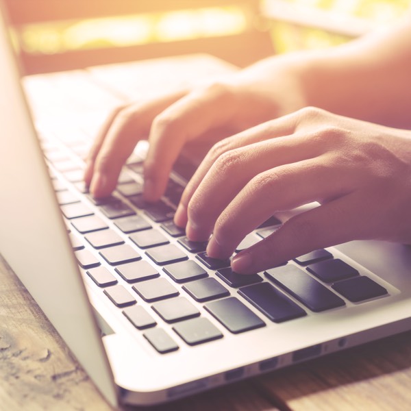 close-up of hands typing on laptop keyboard