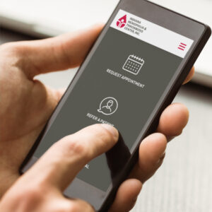 A doctor uses his smartphone to refer a patient to IHTC for additional care