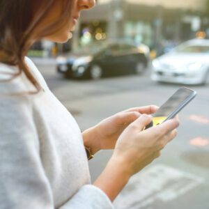 woman walking down the street looking at mobile phone