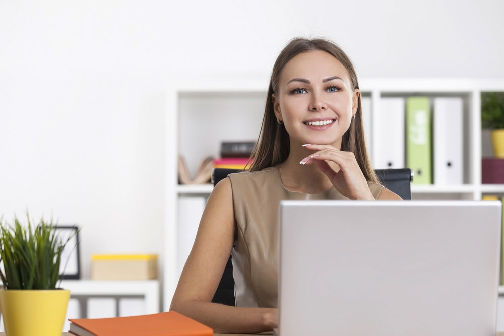 smiling woman sitting at her laptop computer