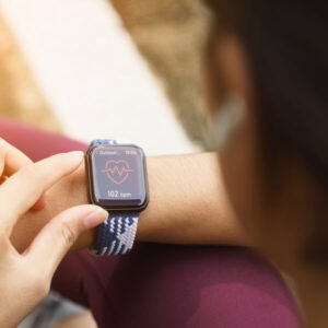 woman uses her smartphone, a form of direct to consumer marketing in healthcare , to check her vitals after exercising