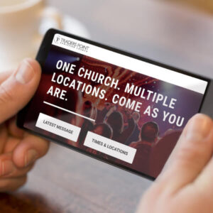Man holding smartphone views the Traders Point Christian Church website redesign