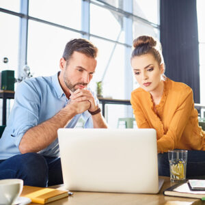 two coworkers intently watching a laptop screen