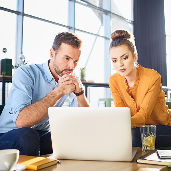 two coworkers intently watching a laptop screen