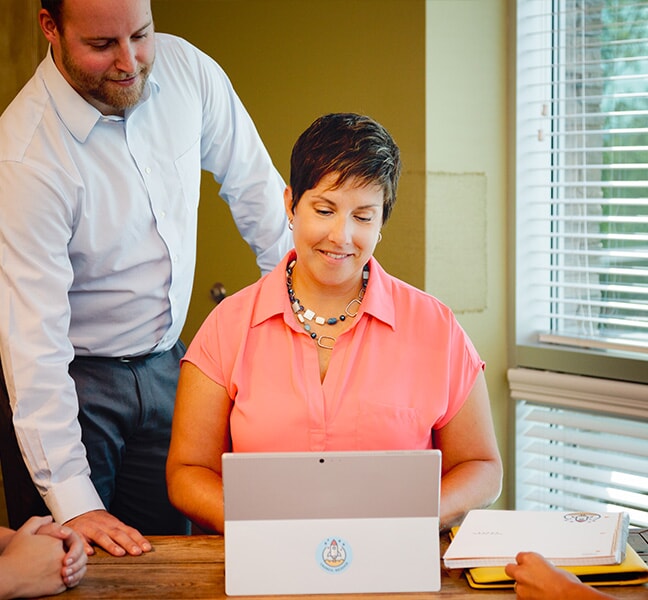 Team members smiling while looking at work on tablet