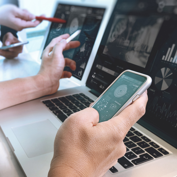 web designer using laptop and holding mobile device