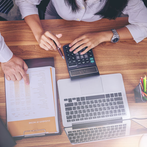people at a desk with a computer and calculator building out a website budget