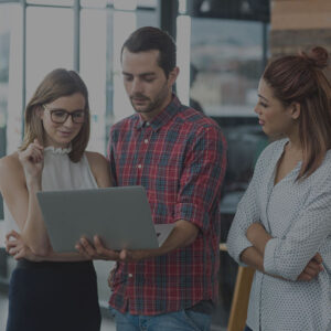 Marketing professionals standing around laptop